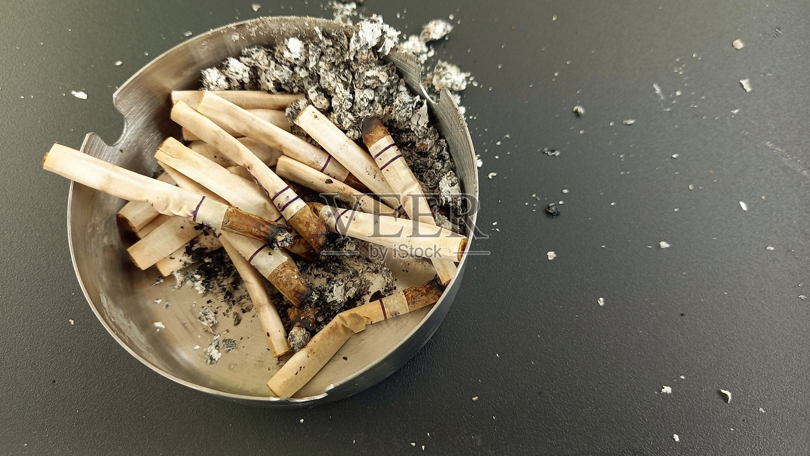 不锈钢烟灰缸里一堆用过的烟头近照照片摄影图片