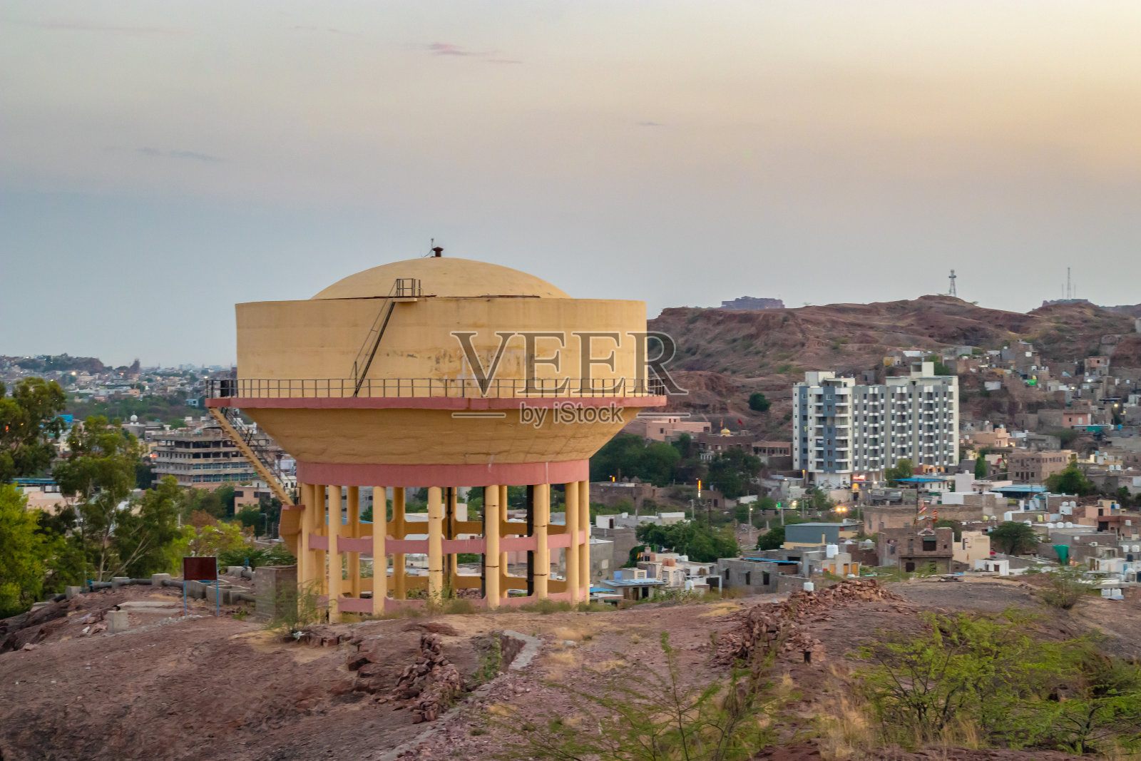 巨大的水箱和城市房屋建筑和傍晚的山脉背景照片摄影图片