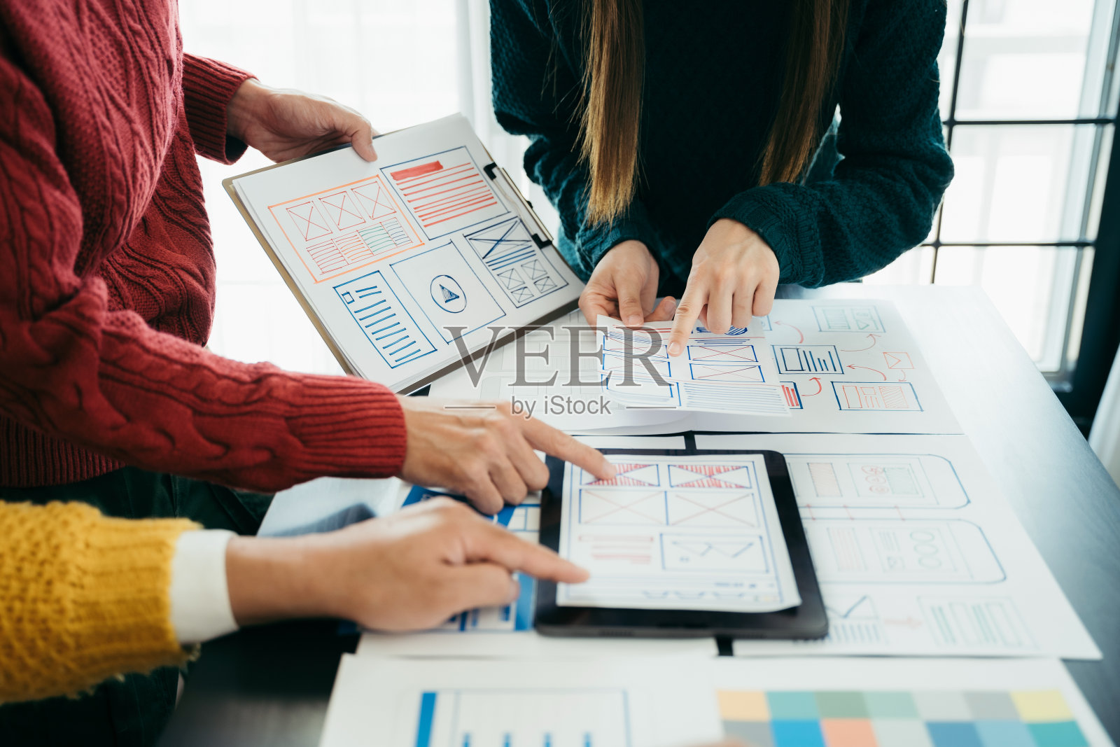 UI设计师在办公室与客户进行头脑风暴，设计手机应用程序界面线框图和颜色代码。照片摄影图片