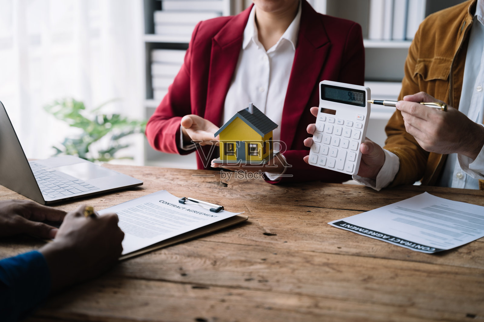房地产经纪人在办公室向客户提出并咨询决策签订保险合同、房屋模型、有关按揭贷款报价照片摄影图片