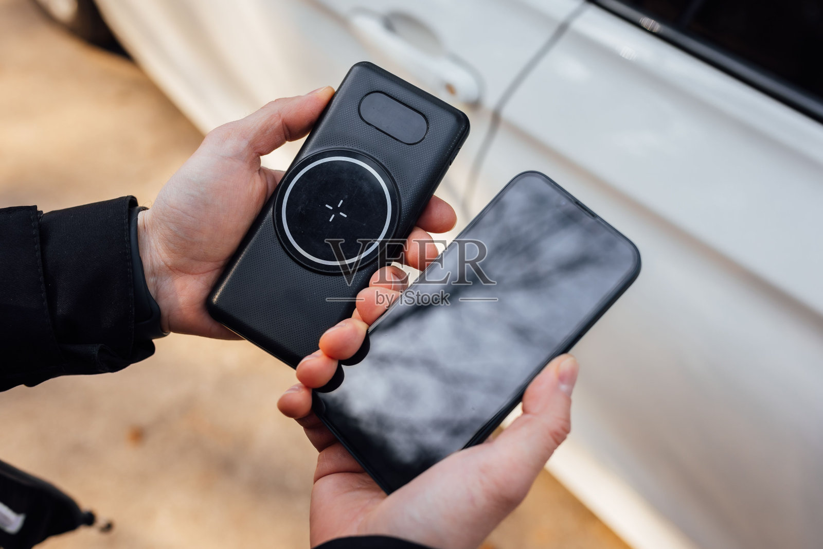 手持智能手机和无线手机充电器的人的手特写照片摄影图片