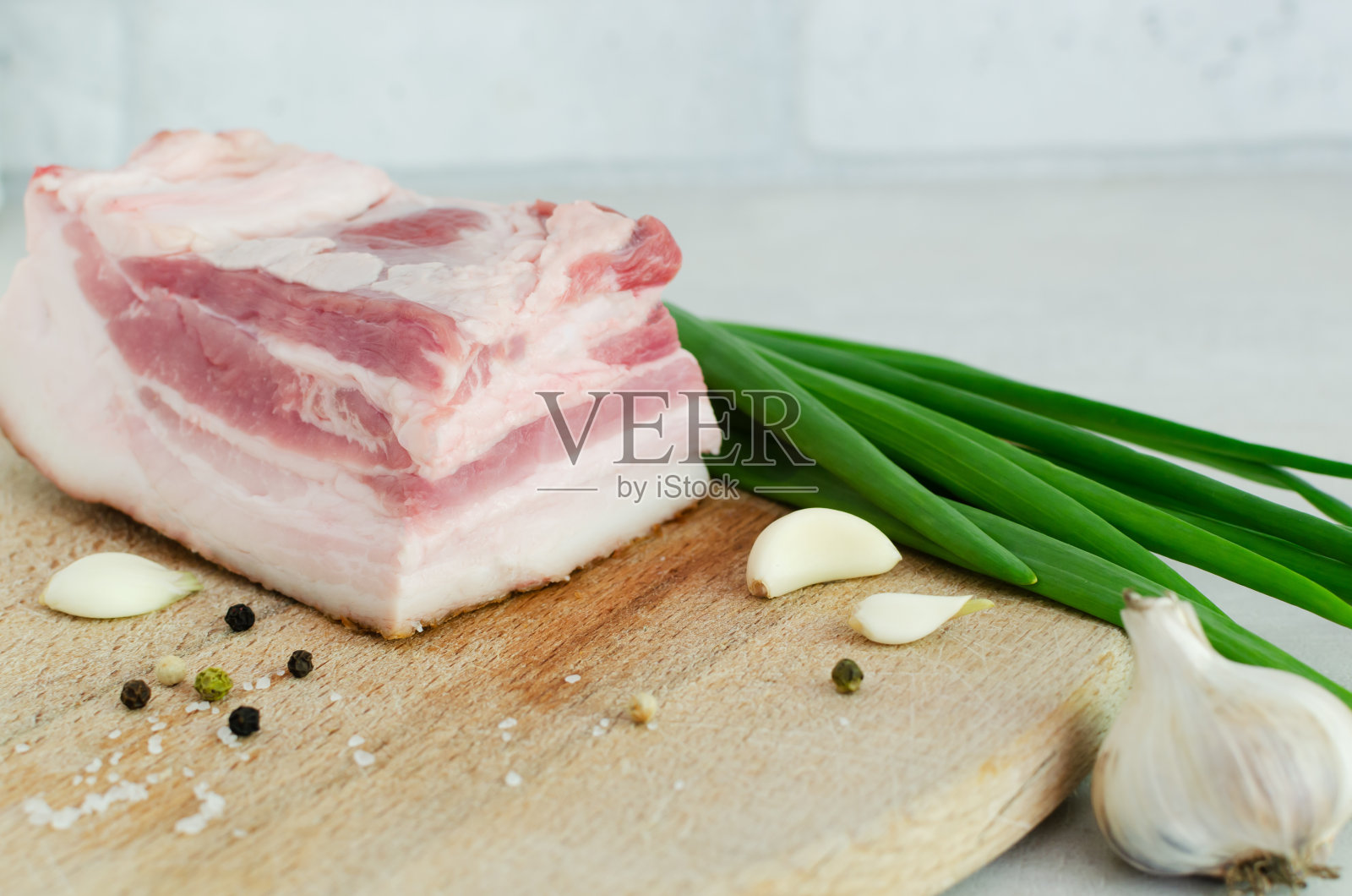 在木板上放上新鲜的咸肉，配上葱和蒜。培根。概念乌克兰传统菜肴。水平方向。有选择性的重点。照片摄影图片