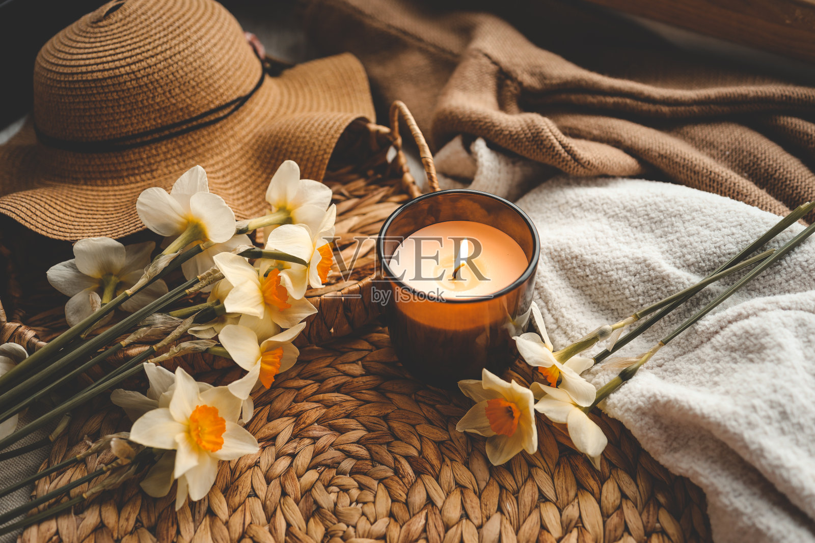 惬意的春天构图，燃烧的蜡烛，水仙花和帽子照片摄影图片