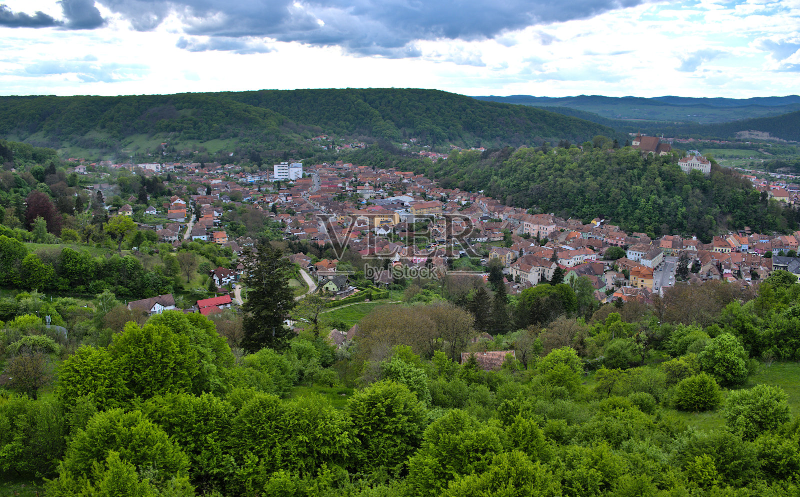 从树木覆盖的山顶俯瞰中世纪城市的共产主义时代建筑照片摄影图片