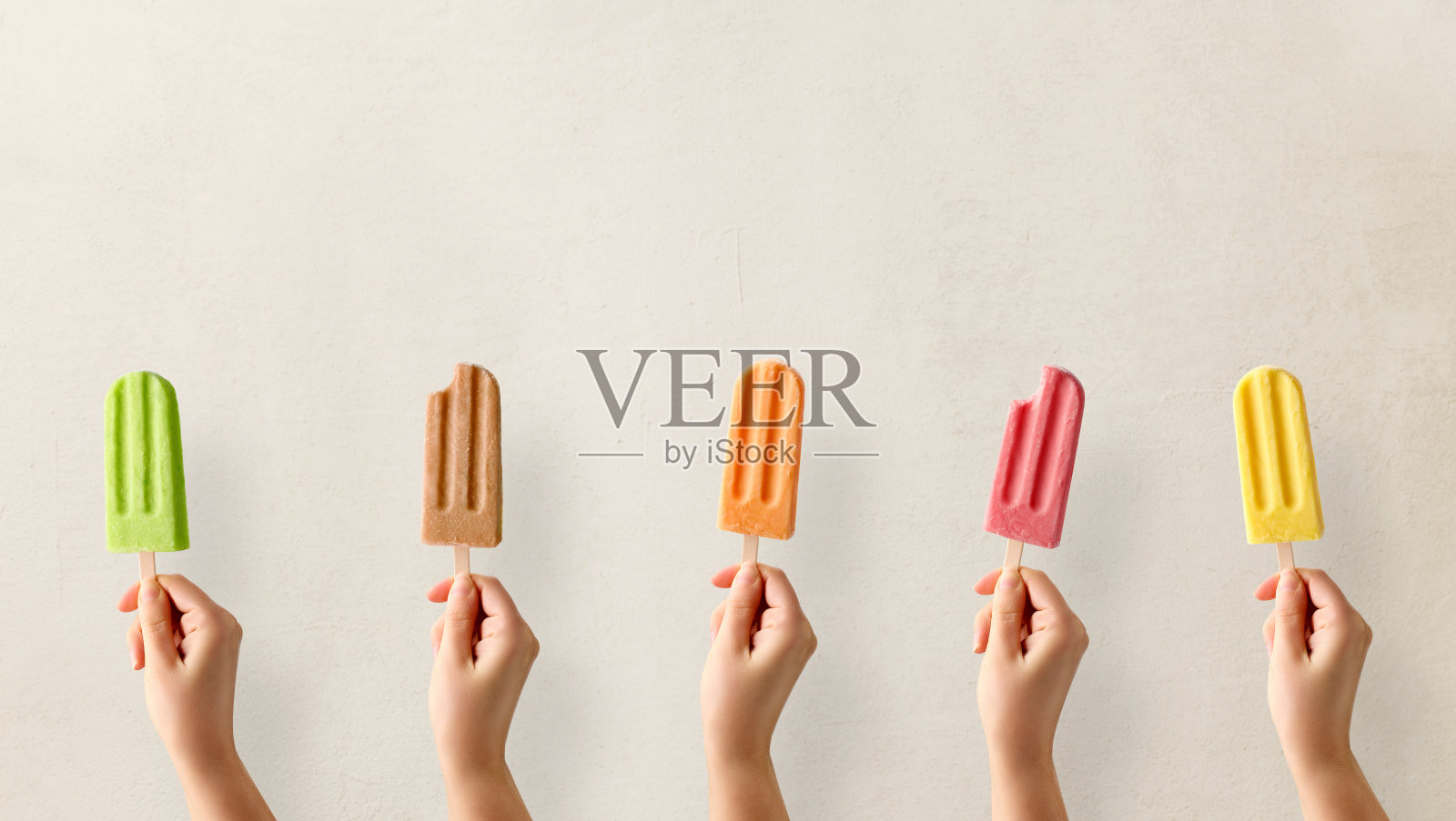 手里拿着五颜六色的水果冰棒照片摄影图片