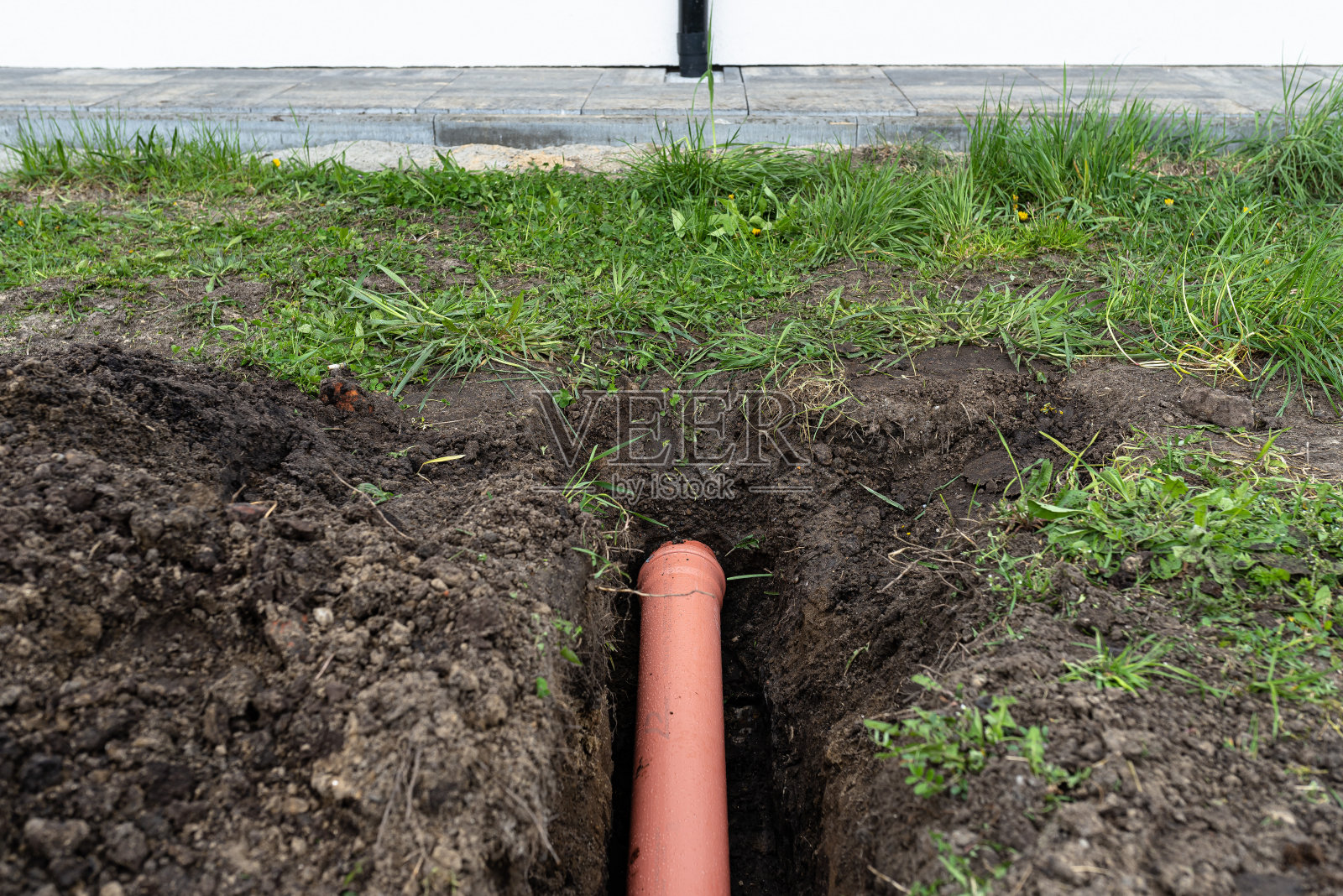 橙色PVC管埋在地下与排水沟相连，用于与排水管相连。照片摄影图片
