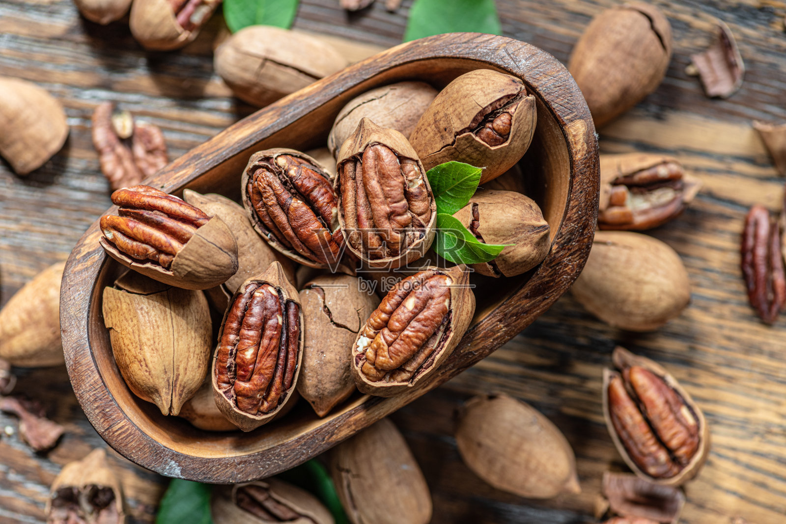 木桌上的木碗里装着剥了壳的山核桃。前视图。照片摄影图片