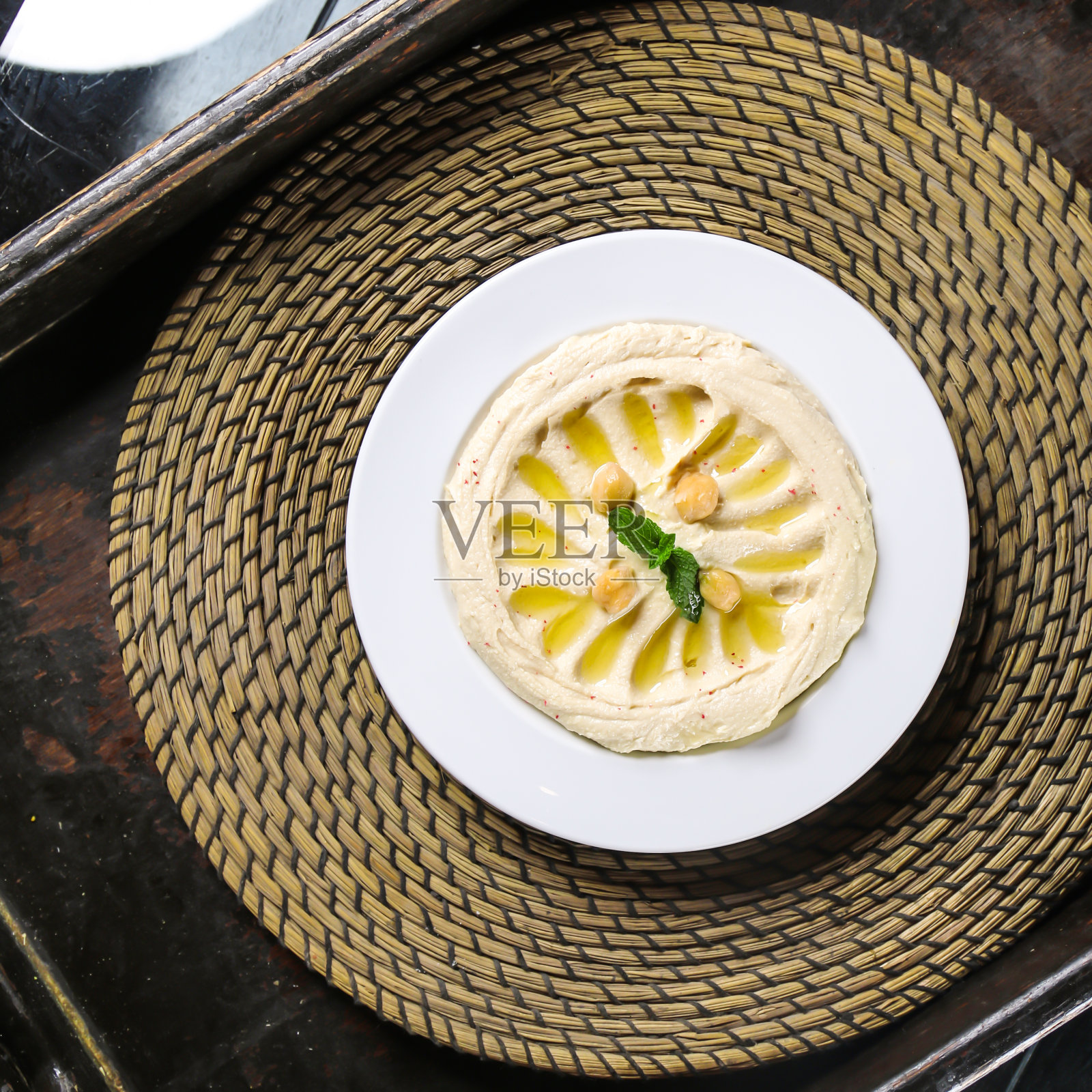 鹰嘴豆泥，阿拉伯食品，菜肴中盛放的鹰嘴豆泥，红色垫子顶部视角。照片摄影图片