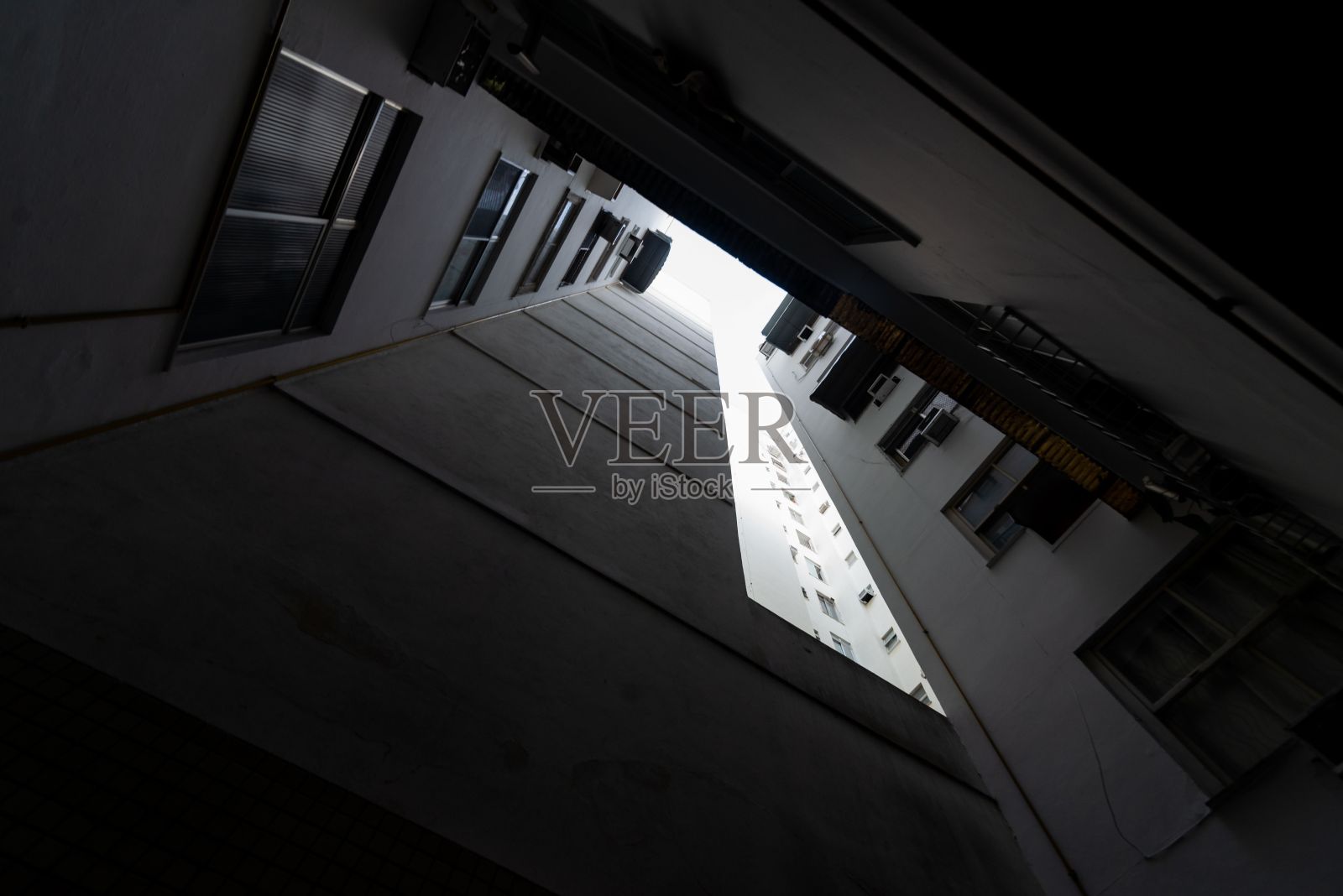 低角度拍摄两栋建筑之间的小巷，展示方形的空间照片摄影图片