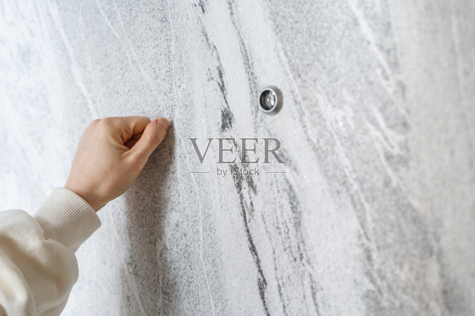 站在门口的女人用手敲着灰色的门照片摄影图片