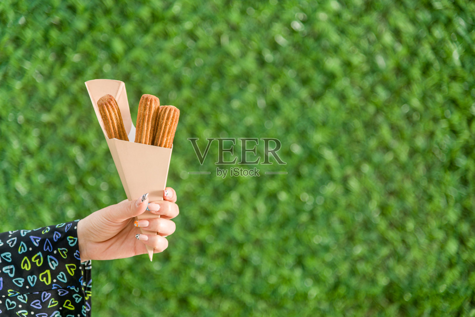 一名妇女在绿草墙前拿着纸板箱里的油条照片摄影图片