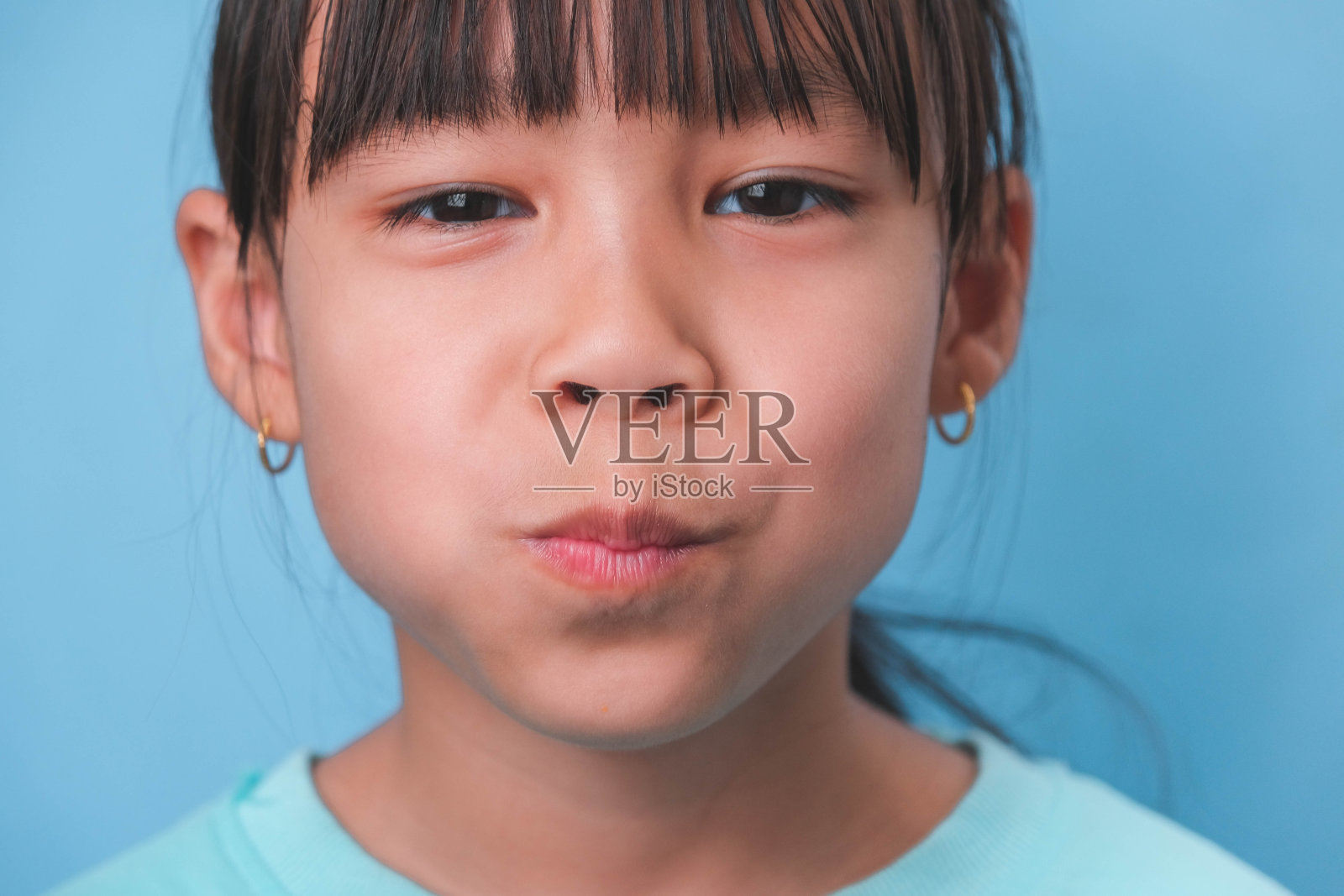 一个微笑的年轻女孩的特写，在蓝色的背景上露出她美丽的白牙齿。儿童健康的概念。照片摄影图片