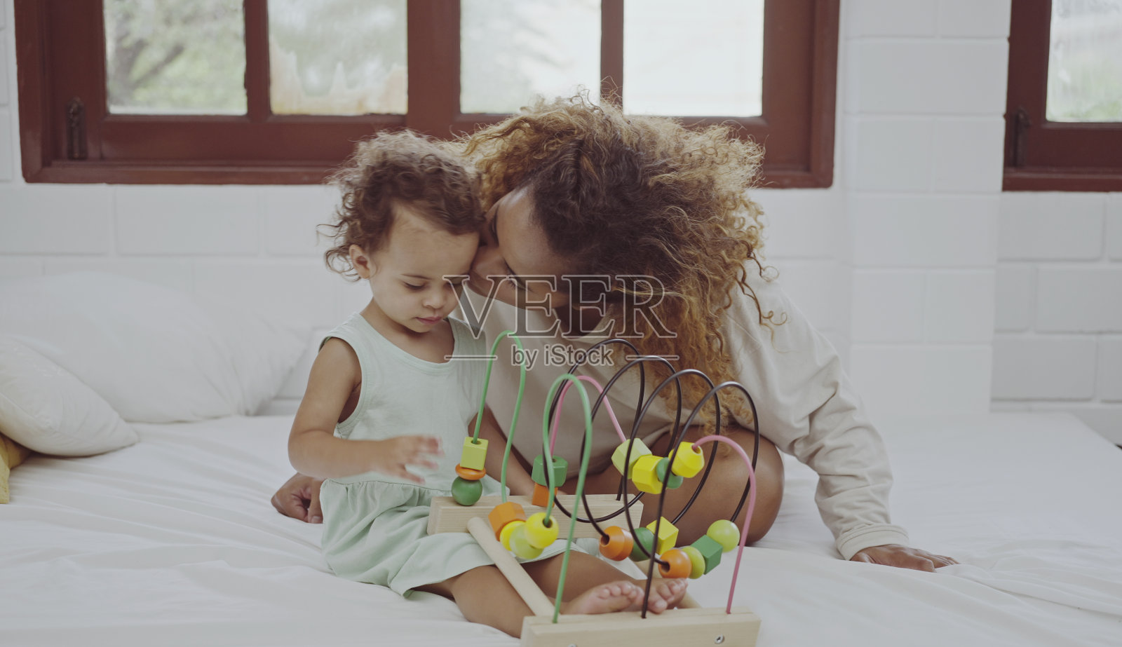 快乐的妈妈和女儿一起在家里的床上玩着五彩缤纷的积木玩具。照片摄影图片