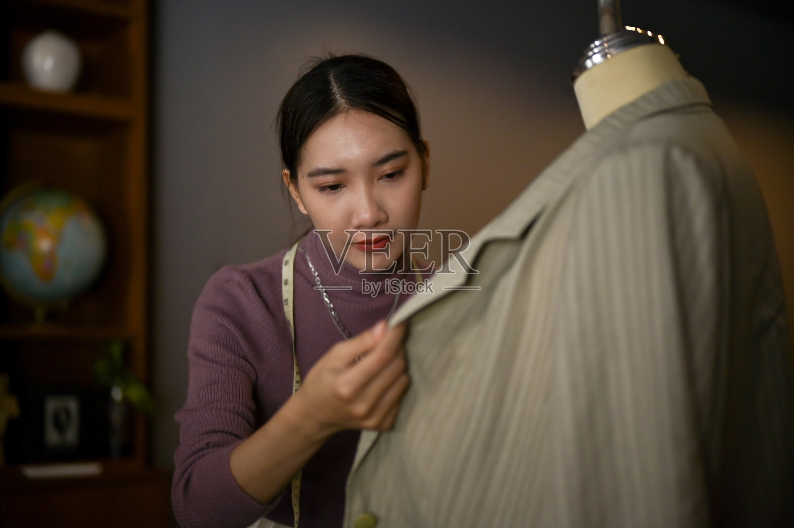 一位女时装设计师在人体模型上检查她的新衣服样品的面料照片摄影图片