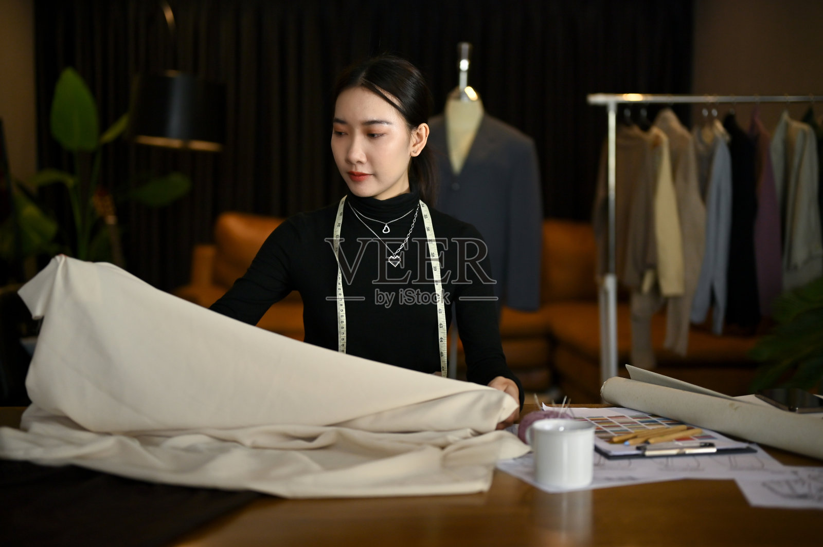 美丽的女时装设计师在工作室里检查面料的质量。照片摄影图片