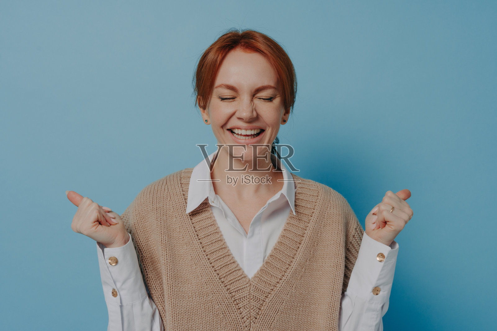 喜出望外高兴激动的红发女在胜利中举起紧握的拳头，孤立上了蓝照片摄影图片