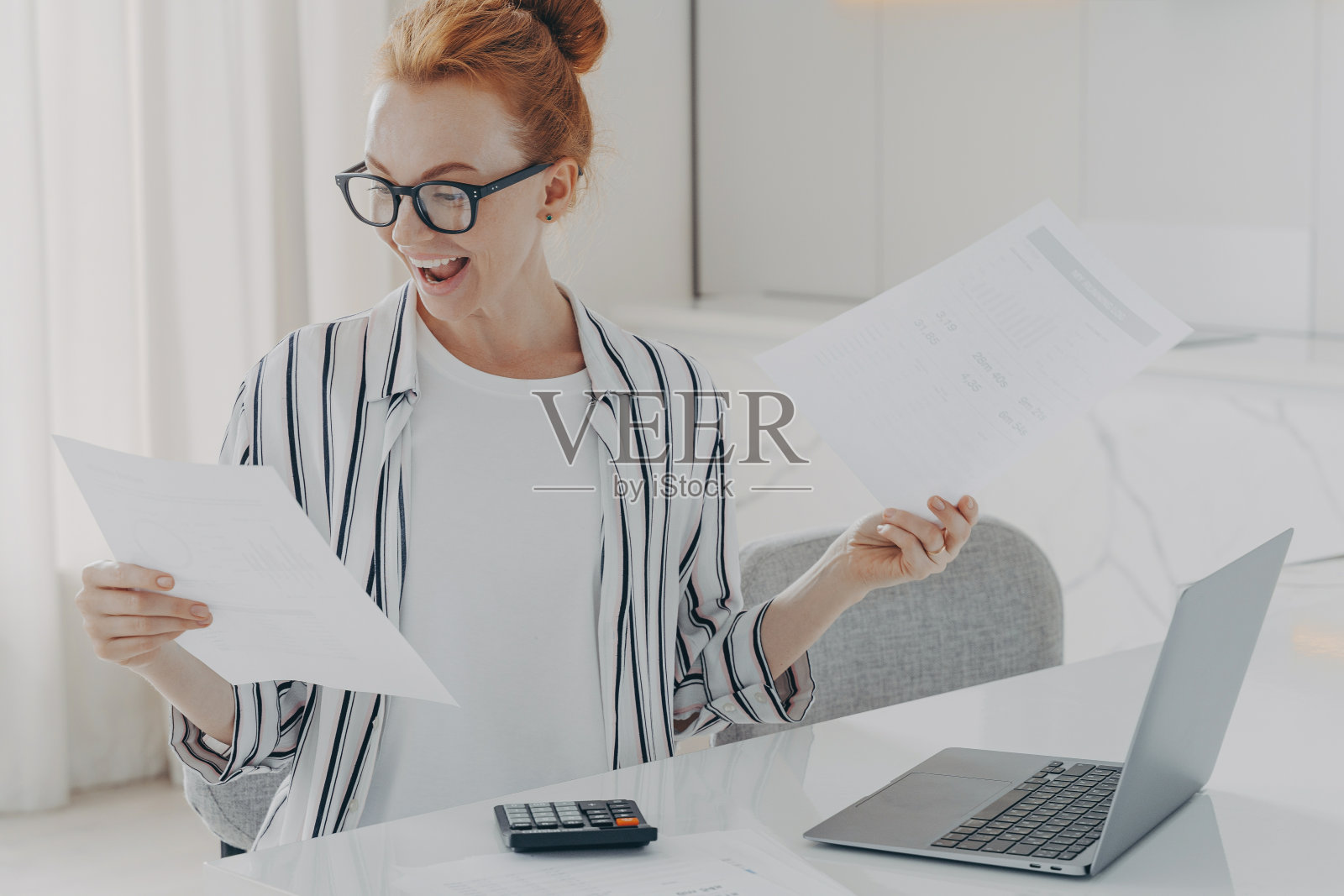 积极的红头发年轻女子正在计算水电费用，从事计划每月预算照片摄影图片