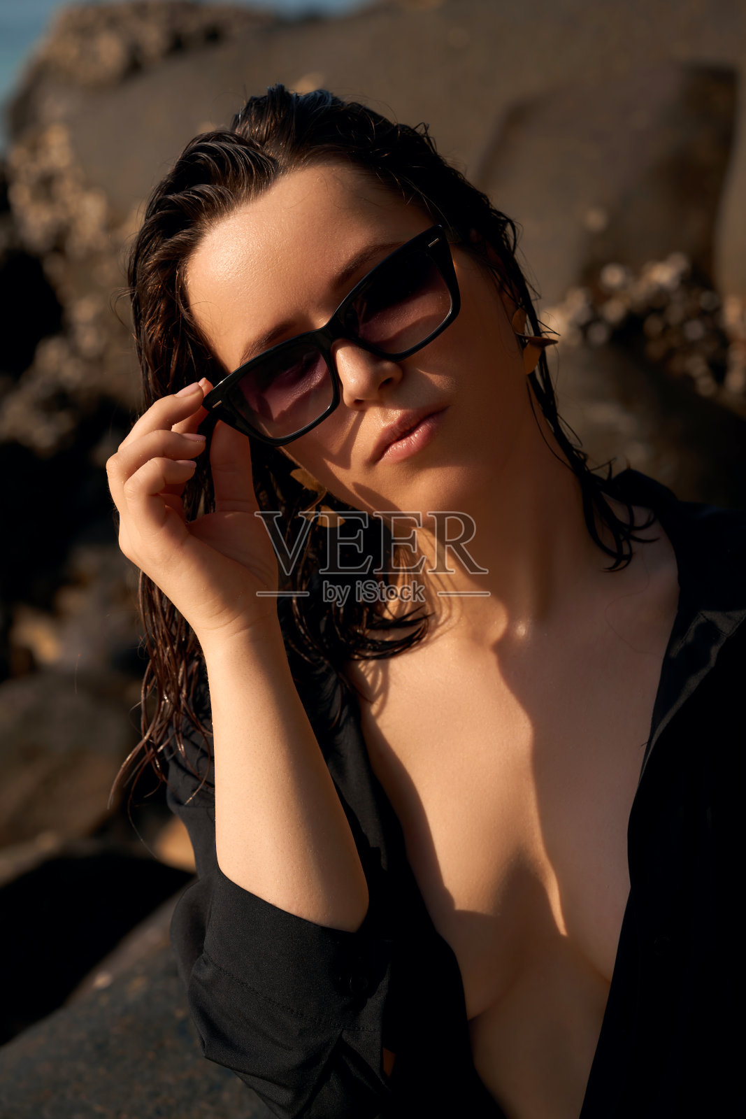 早晨的沙滩上，穿着黑色衬衫的女人戴着金色的首饰和太阳镜照片摄影图片