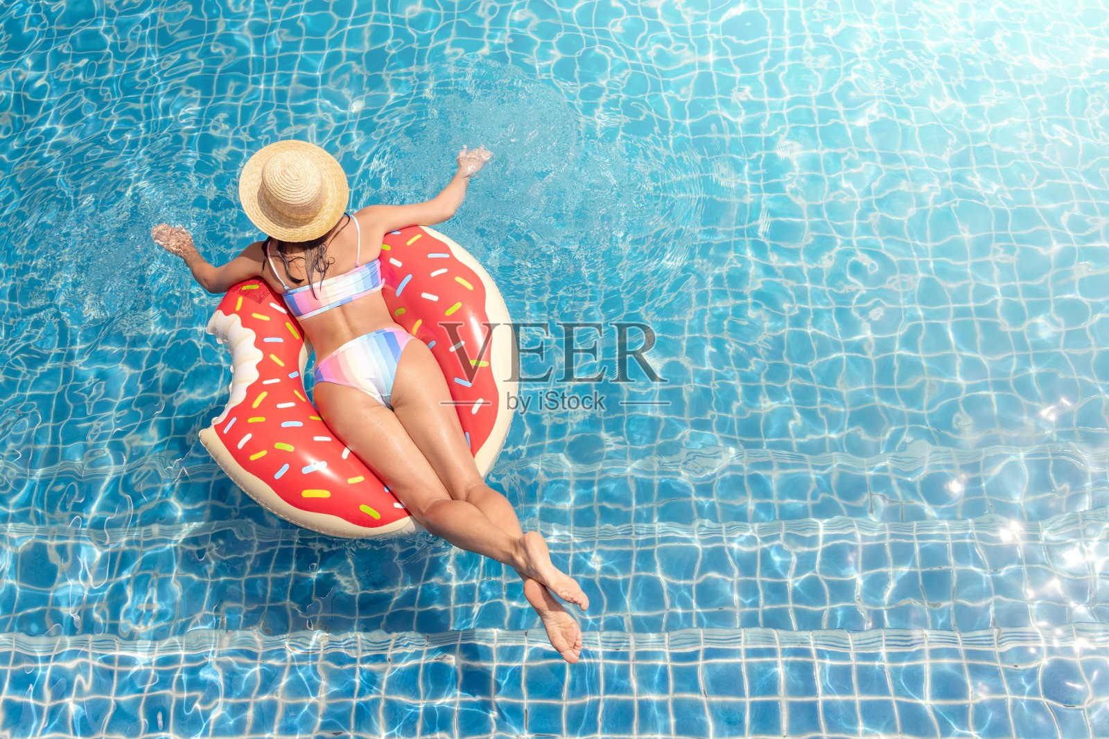 泳池里有充气甜甜圈的美女照片摄影图片