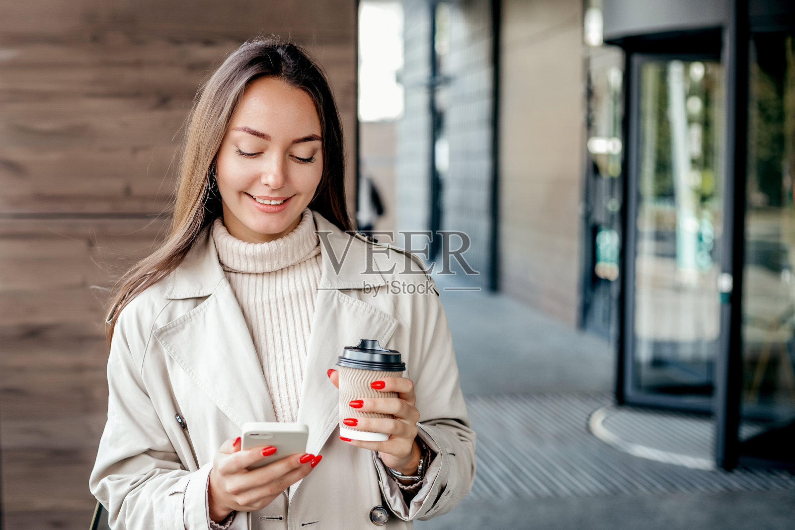 拿着智能手机和办公大楼文件夹的女人照片摄影图片