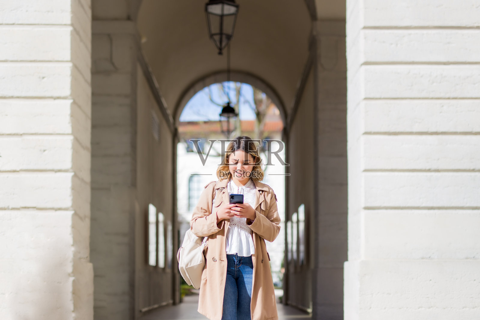 年轻女子在城市里用手机走路照片摄影图片
