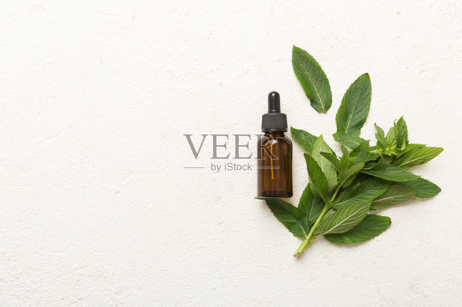 天然薄荷精油在一个玻璃瓶。有机化妆品与草药提取物薄荷在有色背景照片摄影图片