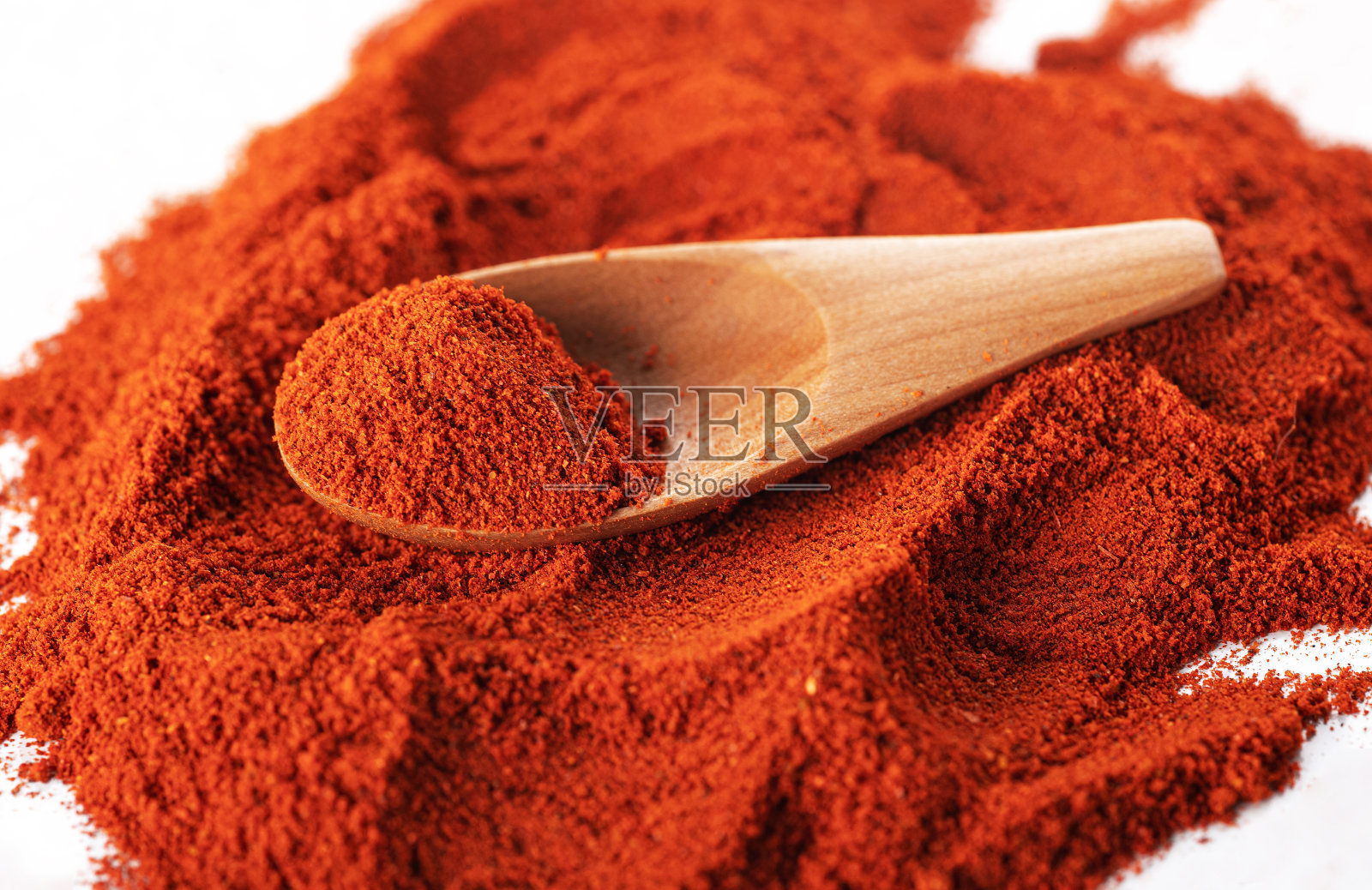 木勺放在辣椒片上，孤立在白色的背景上。一般的观点照片摄影图片