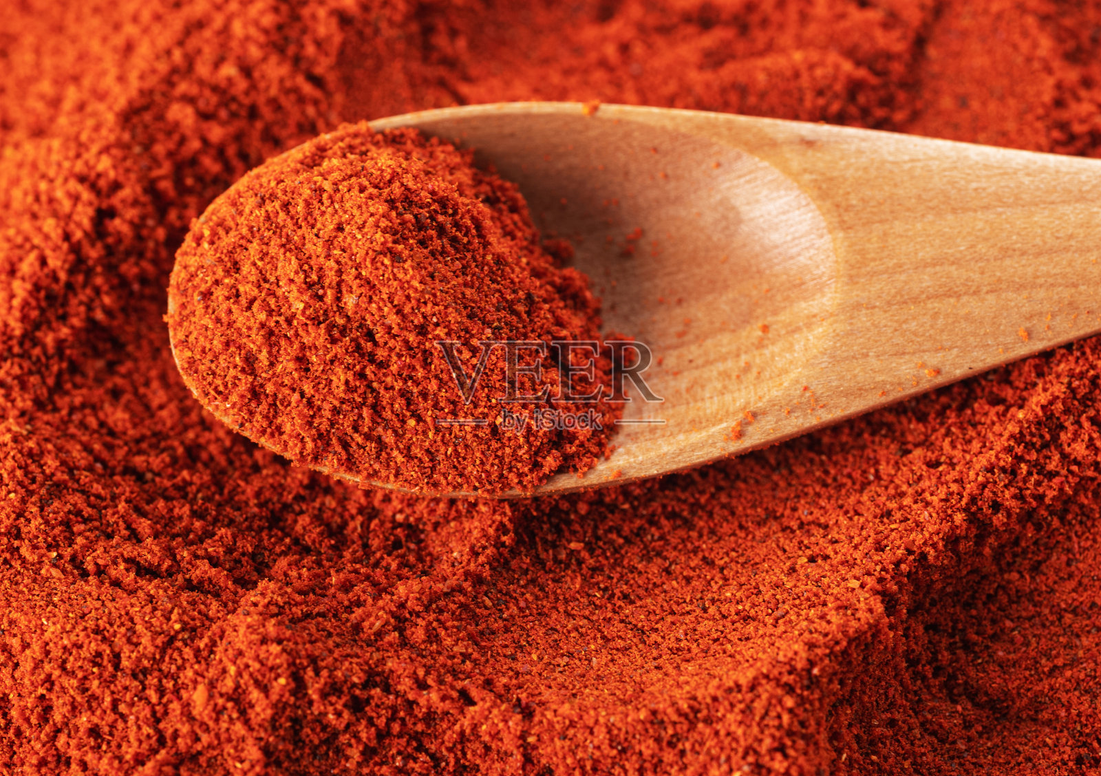 用漂亮的木勺盛辣椒粉。特写镜头。微距摄影。从上面看照片摄影图片