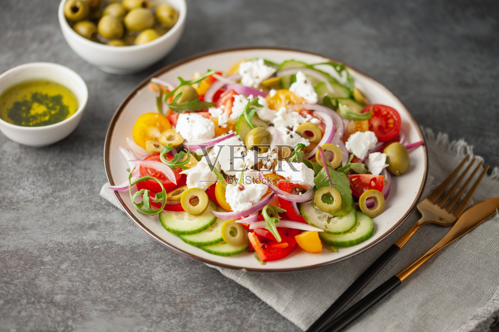 希腊沙拉，由新鲜黄瓜、番茄、甜椒、芝麻菜、红洋葱、菲达奶酪和橄榄油组成。健康食品。照片摄影图片