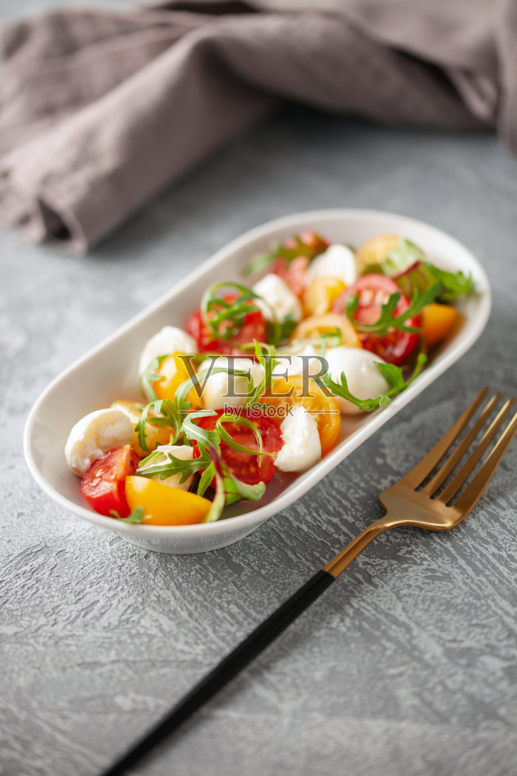 桌上的盘子里有芝麻菜、马苏里拉奶酪和西红柿沙拉。意大利番茄沙拉。照片摄影图片