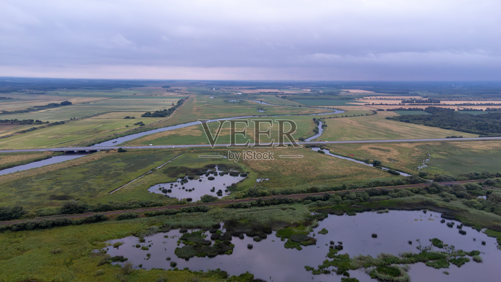 池塘的航拍图，背景是广阔的绿色田野。Romo,丹麦。照片摄影图片