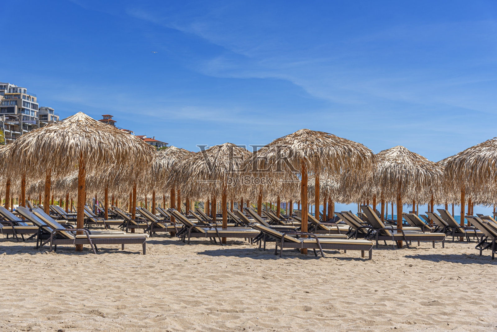 海边的草编沙滩伞和躺椅。照片摄影图片