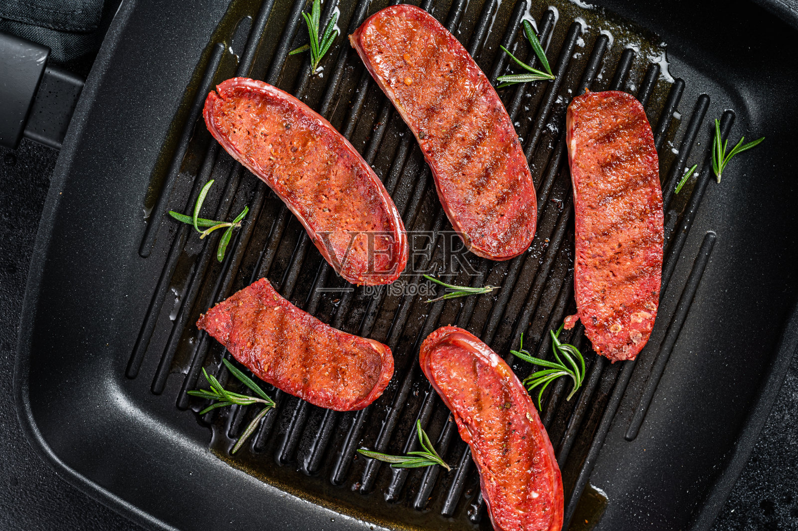 在烤锅上煎土耳其Sucuk肉香肠。黑色背景。俯视图照片摄影图片