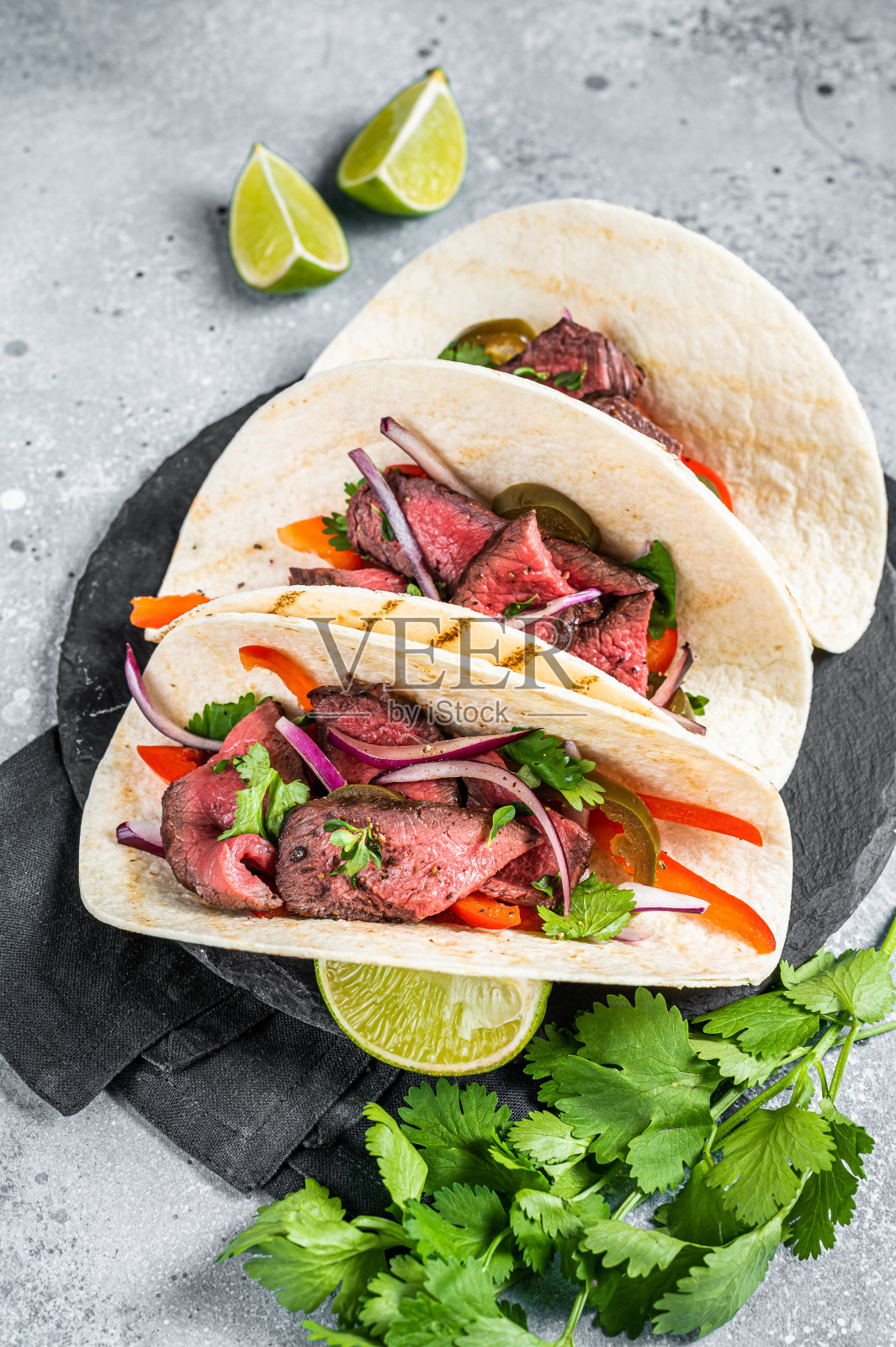 自制墨西哥牛排街玉米饼配香菜，绿酱，墨西哥胡椒和洋葱。灰色的背景。俯视图照片摄影图片