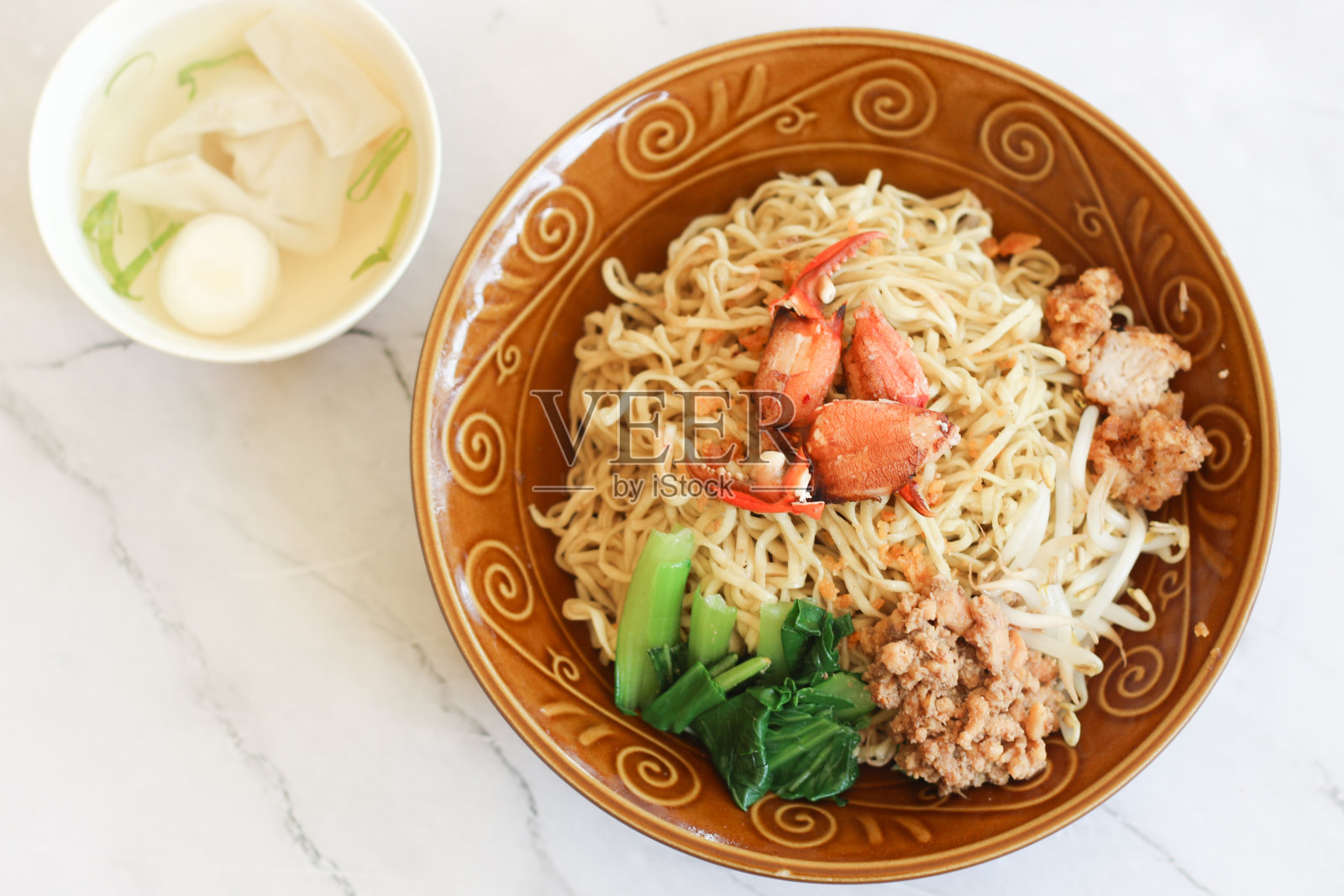 面条上面有碎鸡、豆芽、蔬菜、螃蟹，配上盛有虾baso和饺子的肉汤。照片摄影图片