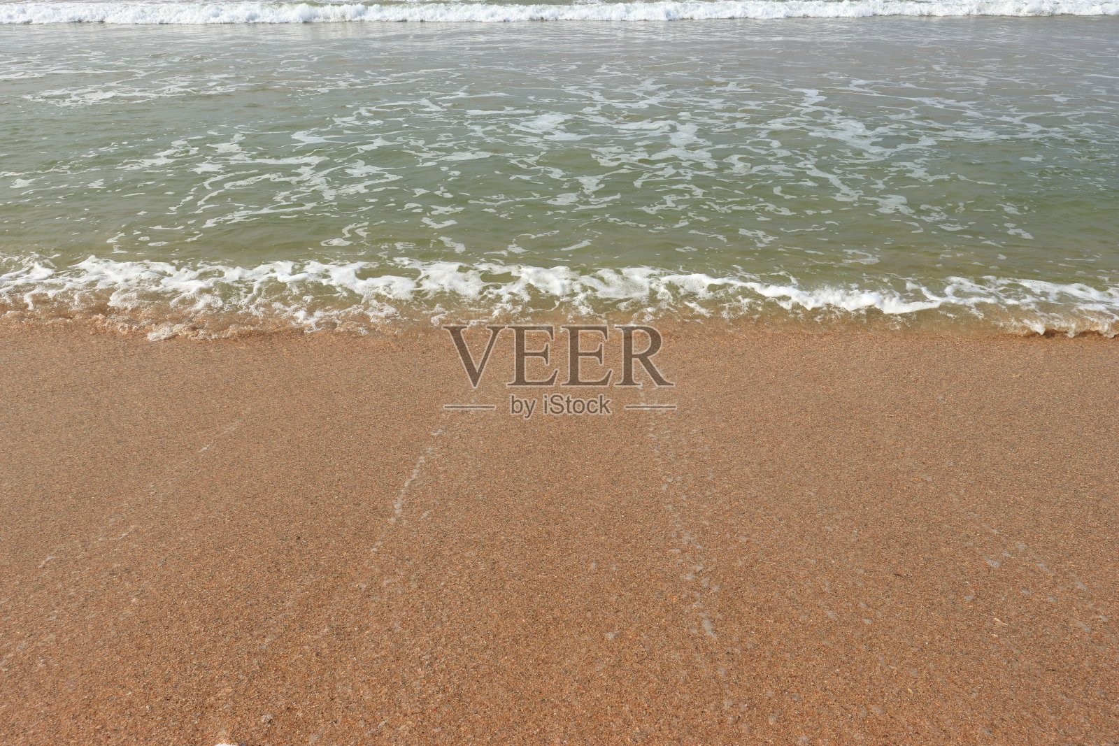 海边有沙滩和前进的波浪。照片摄影图片