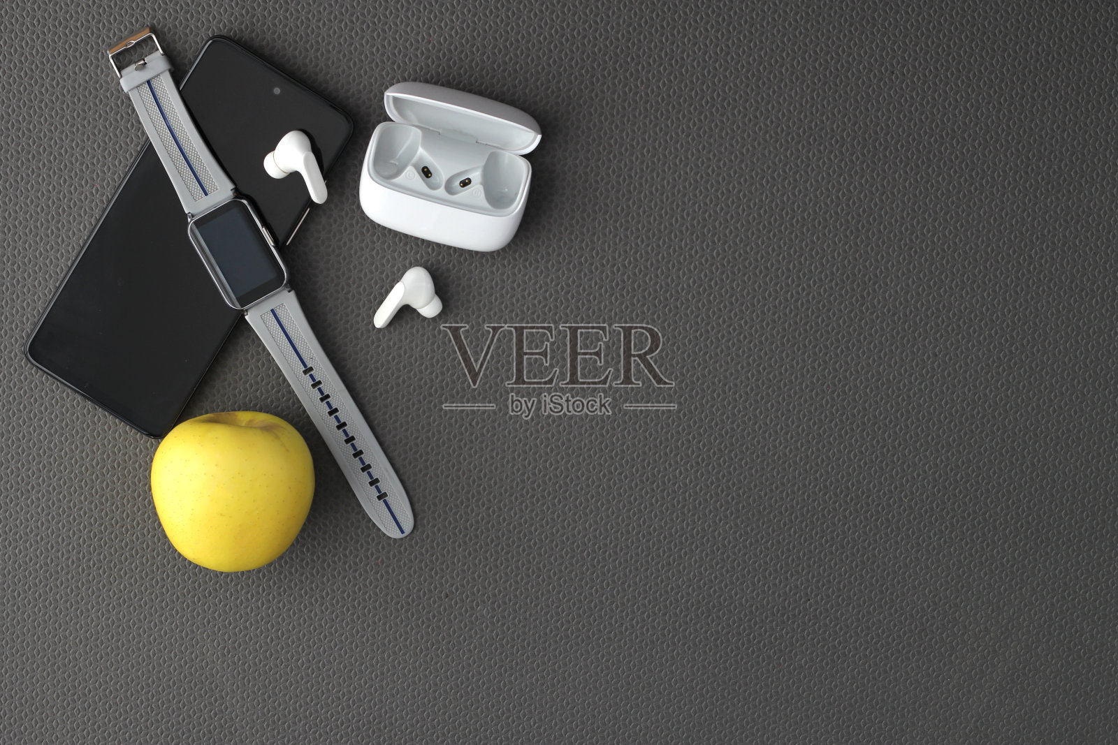 在瑜伽垫上锻炼的物品，如耳机、手机、水、毛巾和苹果，健康的生活和幸福照片摄影图片