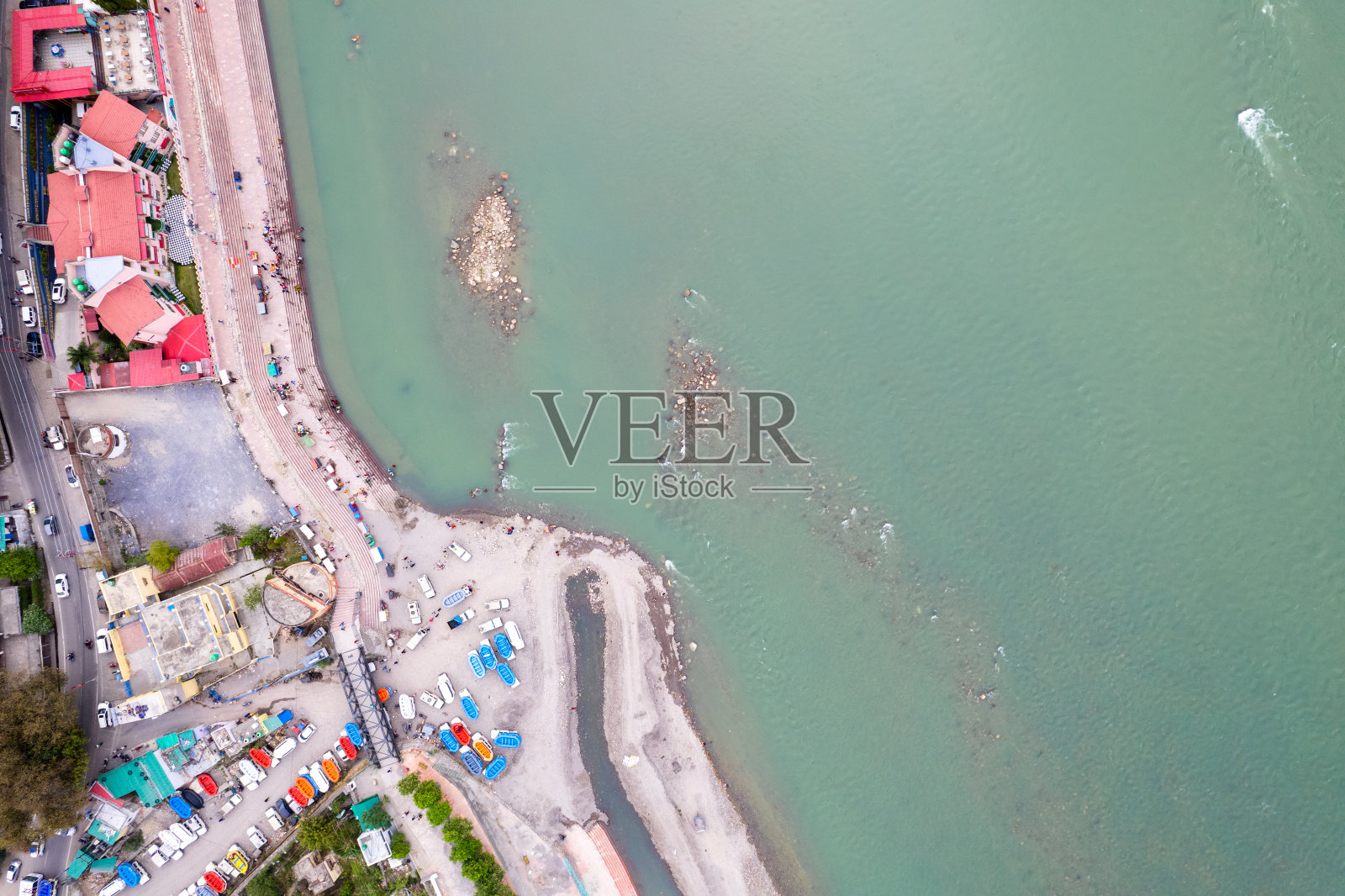 空中无人机拍摄的照片显示，在里希克什的恒河蓝色水域上，人们在河岸的高止山脉上观看水上冒险运动照片摄影图片