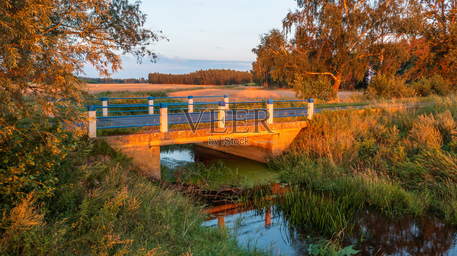 夕阳下横跨河流的公路桥照片摄影图片