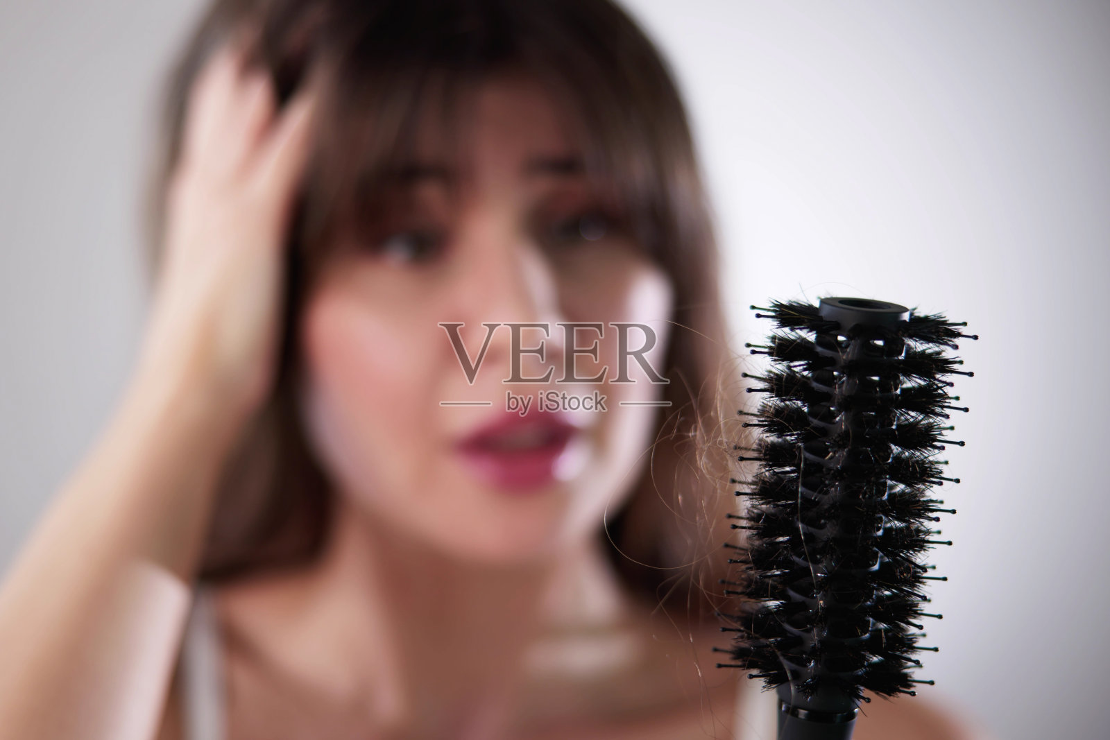 穿着浴袍的年轻女子拿着梳子看着头发脱落照片摄影图片