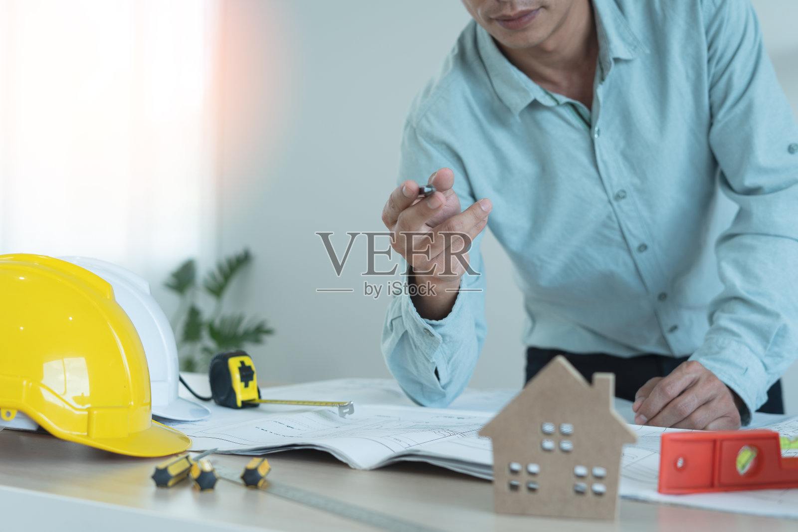 男工程师站在办公桌前，准备撰写和审查用于合资企业建造商业大楼的蓝图。工程师，建筑师的概念照片摄影图片