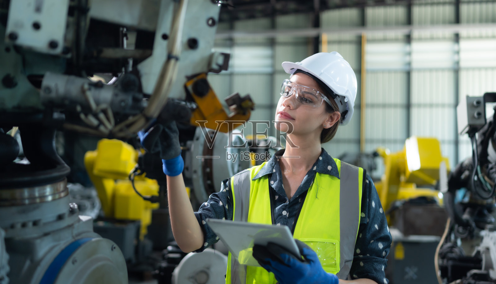 一名女工程师在机器人仓库的机器人手臂上安装程序。并在送机给客户前进行操作测试。照片摄影图片