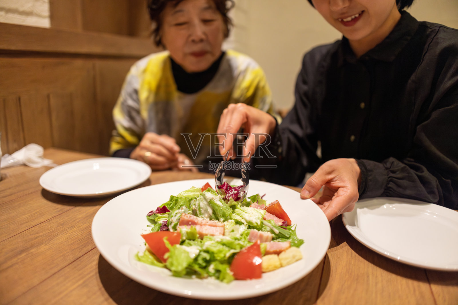 年轻女子和祖母在意大利餐厅吃午餐，餐厅里有沙拉照片摄影图片