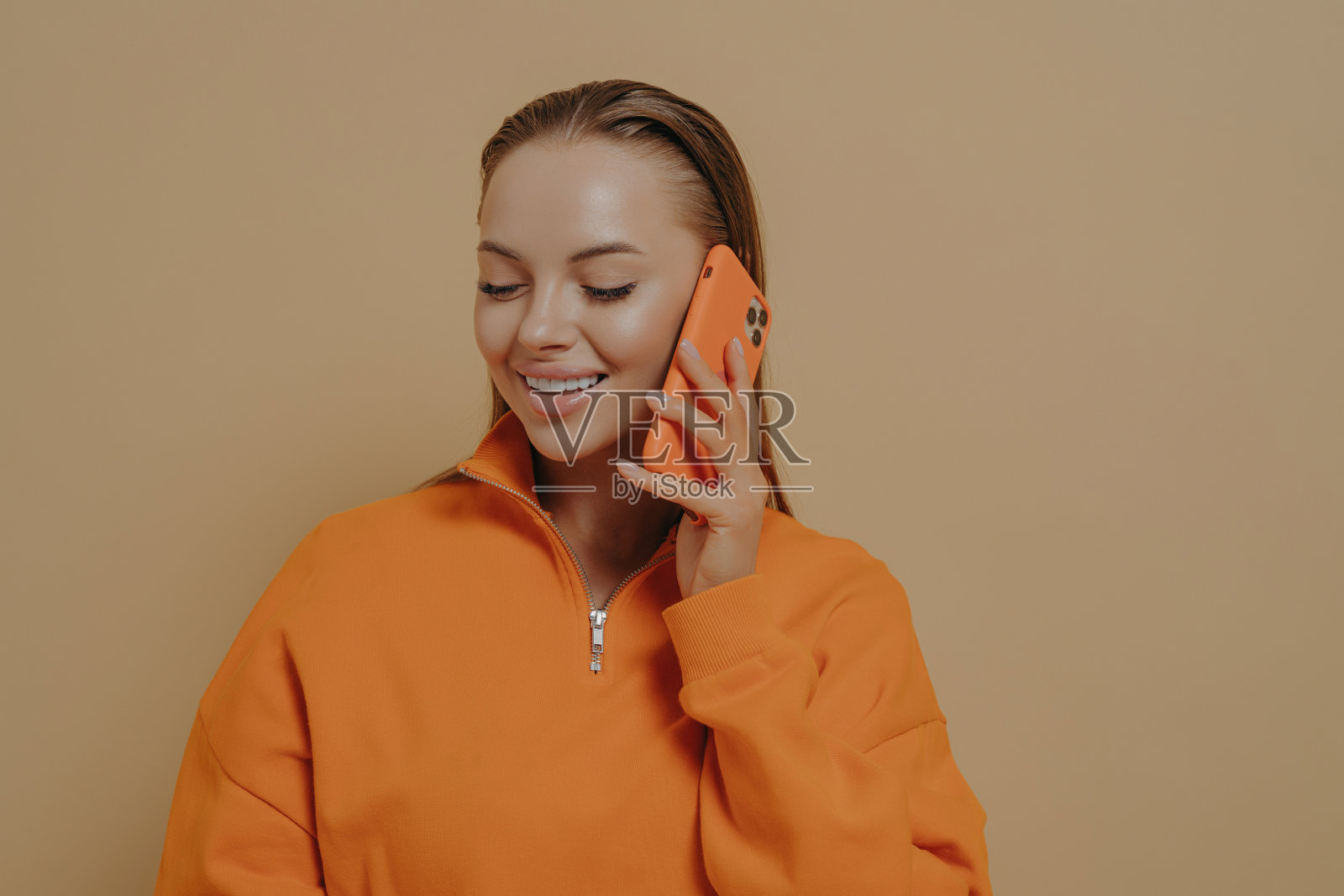 快乐的年轻女子在手机上与朋友交谈，享受电话交谈，孤立在米色照片摄影图片