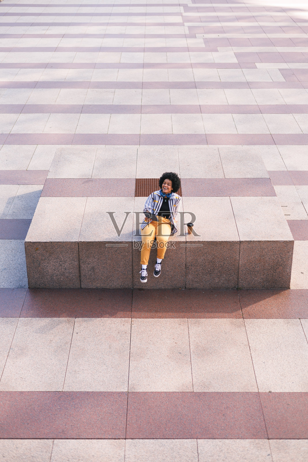 非裔多米尼加妇女坐在现代户外使用平板电脑，复印空间照片摄影图片