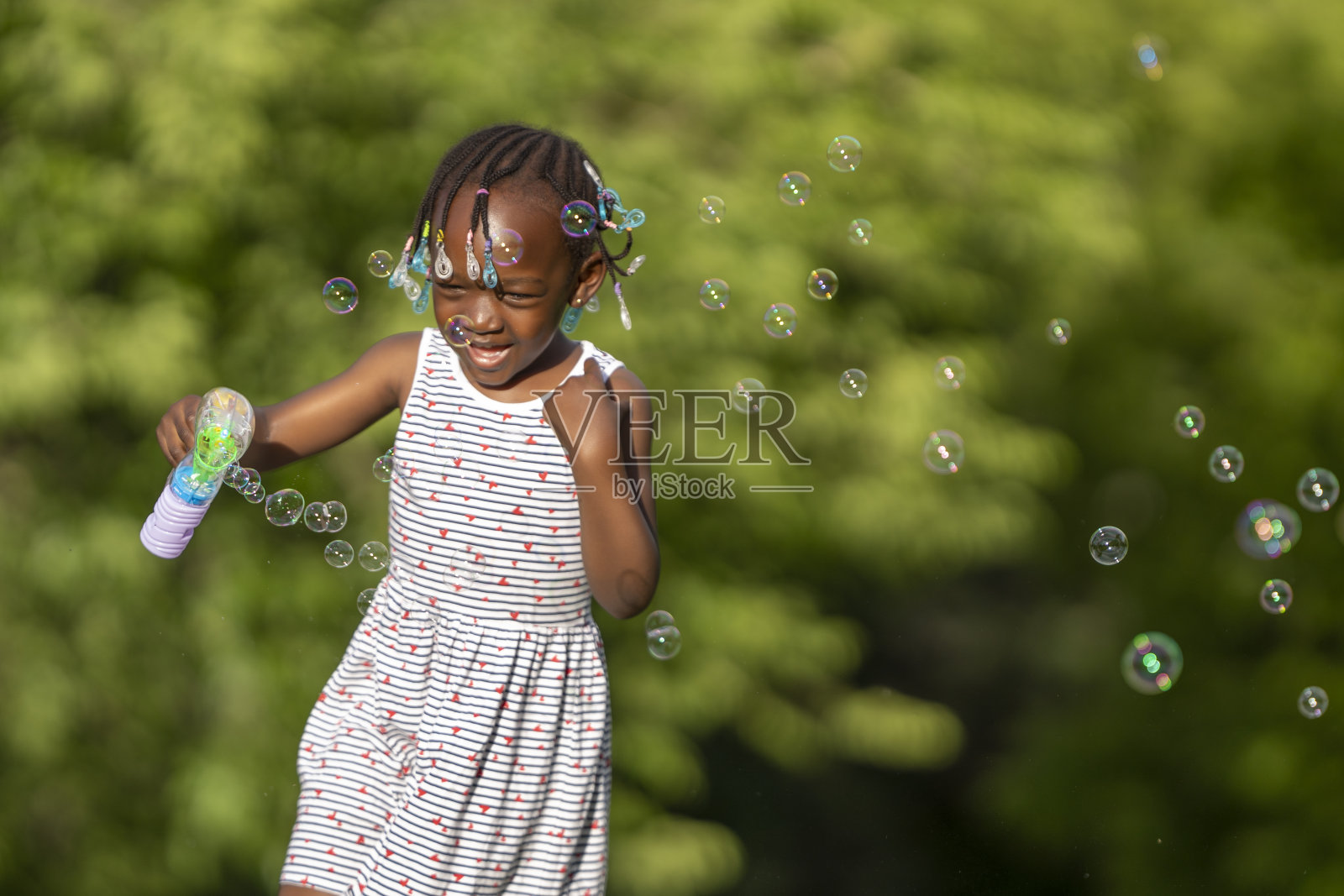 一个黑皮肤的女孩在公园里玩肥皂泡照片摄影图片