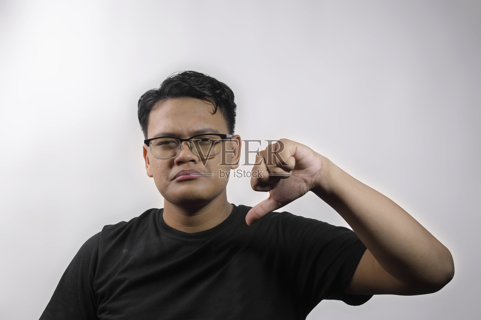 年轻英俊聪明的亚洲男子在白色背景上展示拇指向下的手势照片摄影图片