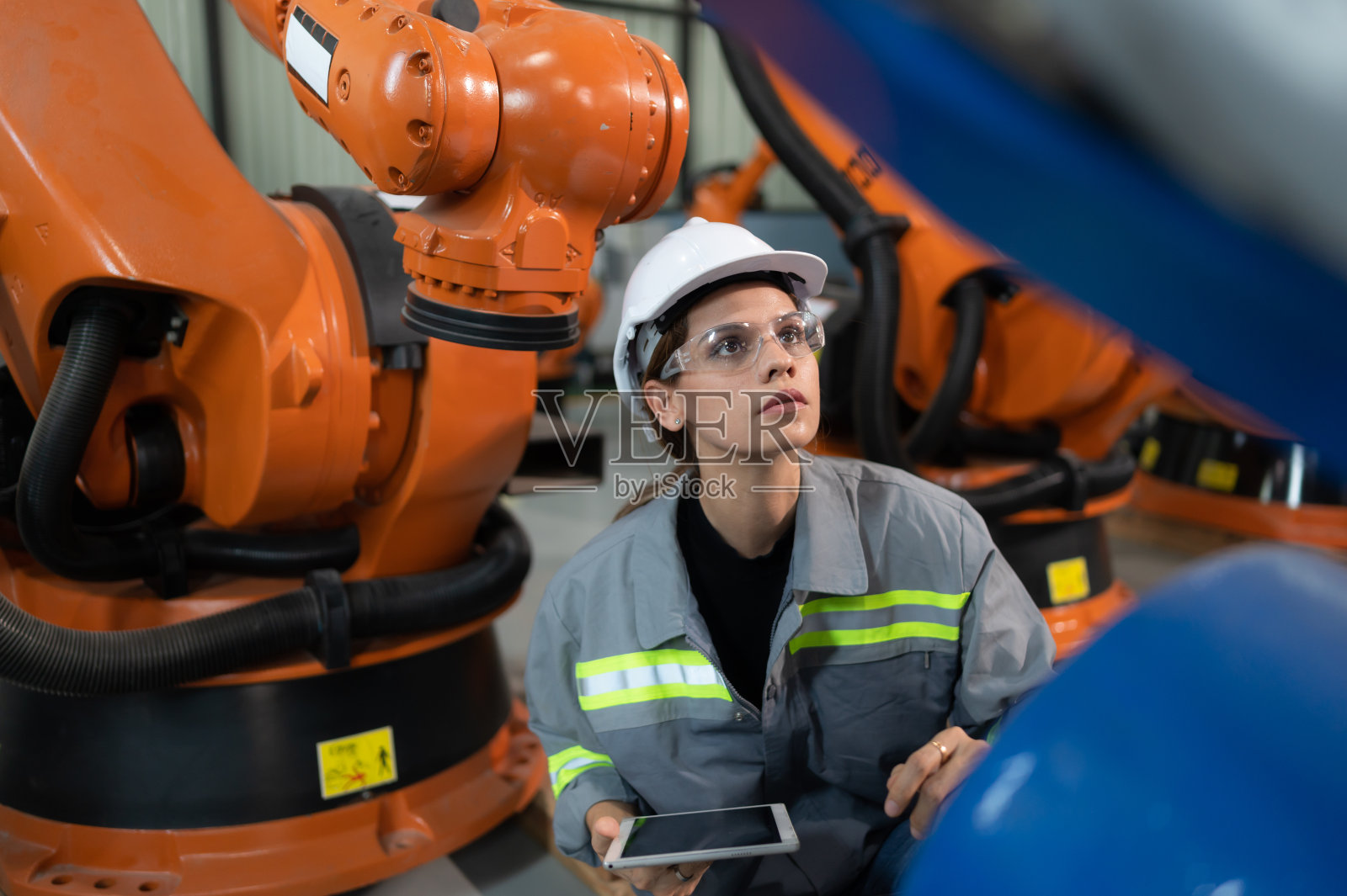 一名女工程师在机器人仓库的机器人手臂上安装程序。并在送机给客户前进行操作测试。照片摄影图片