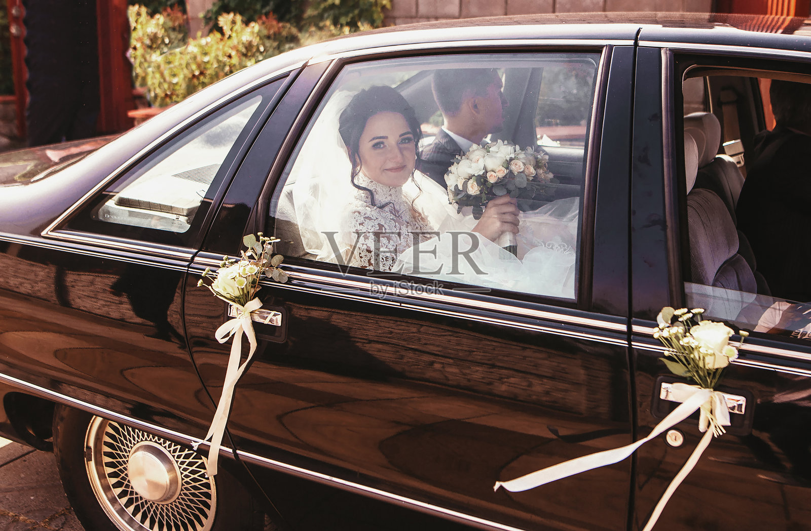 幸福的新婚夫妇坐在车里。新娘和新郎在车里照片摄影图片