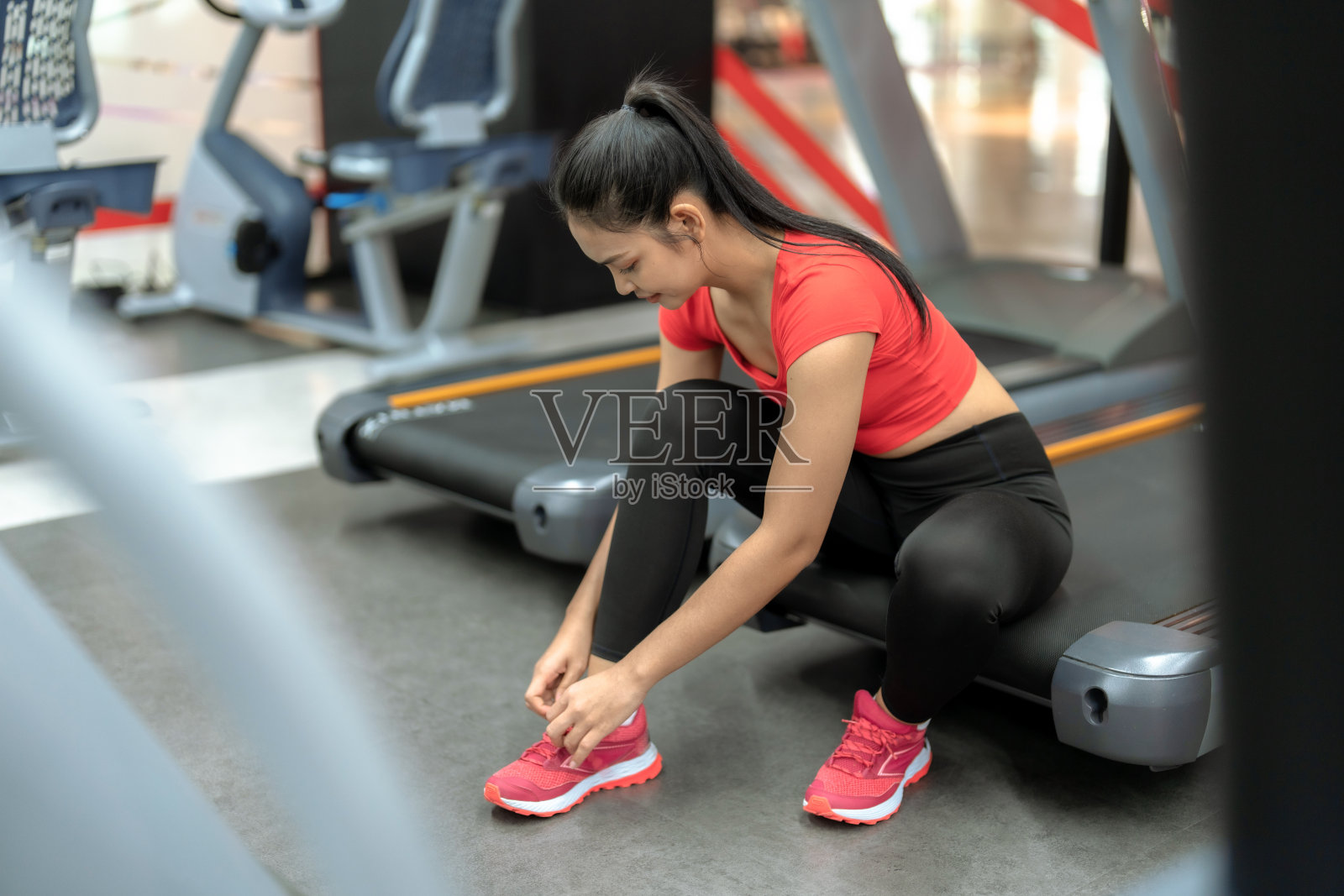 亚洲妇女在健身房系鞋带准备锻炼。照片摄影图片